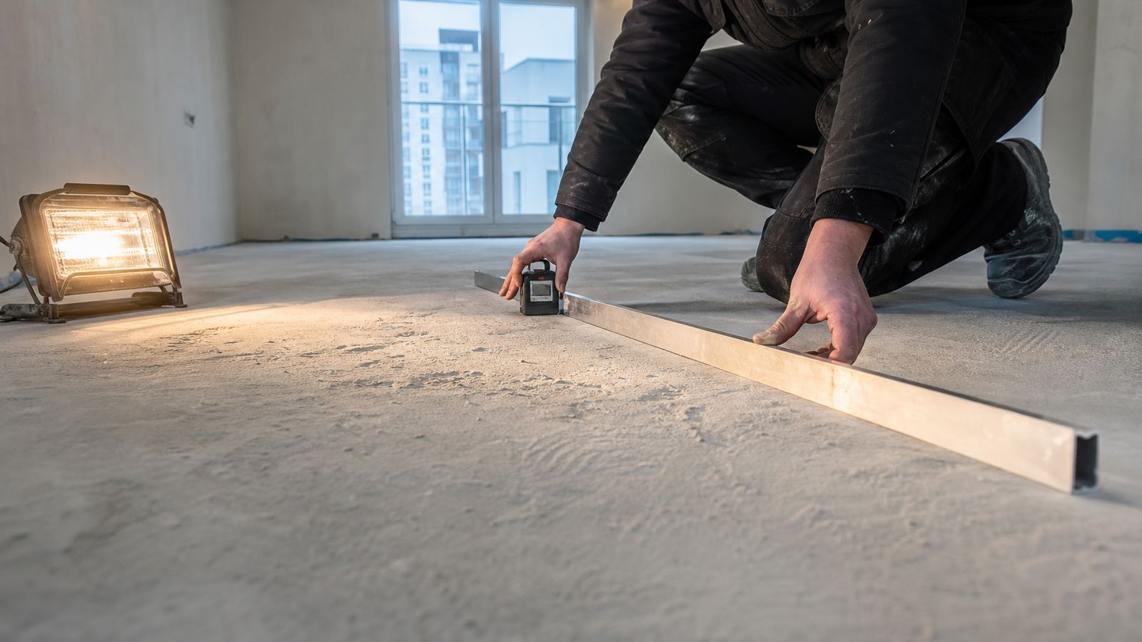 Inspector checking wall and floor geometry in a new Polish apartment