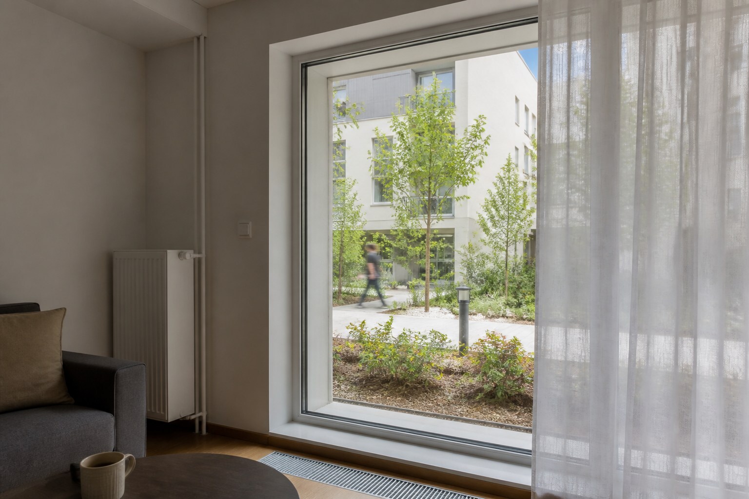 View from a ground-floor Warsaw apartment towards a shared courtyard and pedestrian path