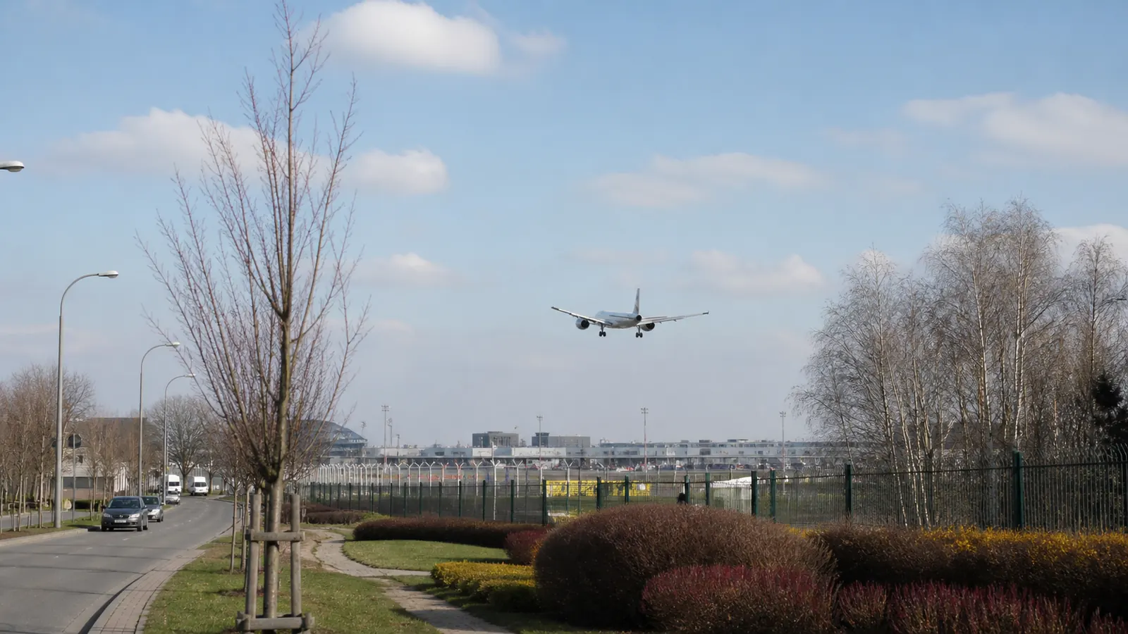 Passenger aircraft approaching Warsaw Chopin Airport beside a Włochy street